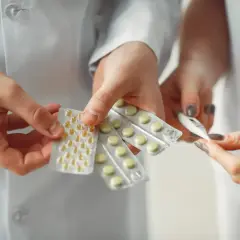 Lekarz od tarczycy trzyma tabletki i termometr.