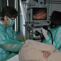 Lekarze w zielonych fartuchach przygotowują się do gastroskopii, monitorując obraz z endoskopu.