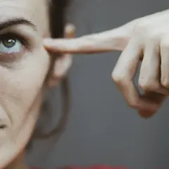 Dłoń naciska na skroń kobiety, jakby szukając zadośćuczynienia za ból głowy.