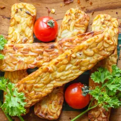Złociste kawałki tempeh, smażone na złoto, z pomidorkami i natką pietruszki. Tempeh co to? To pyszna, roślinna alternatywa!