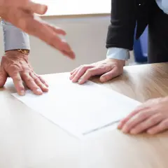 Dwie osoby przy biurku omawiają dokumenty, być może rozwiązanie umowy o pracę.