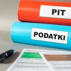 Dwa segregatory z napisami "PIT" i "PODATKI" oraz formularze podatkowe i długopis. Czas na ulgę podatkową!