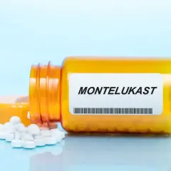 Pomarańczowa buteleczka leku z etykietą "MONTELUKAST" i rozsypanymi tabletkami.