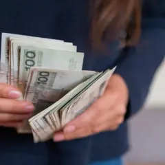 Dłonie liczą banknoty 100 zł. To może być darowizna od rodziców na nowy cel.