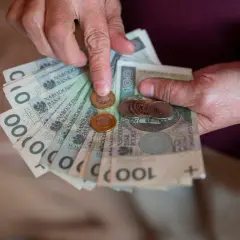 Dłonie liczą banknoty i monety. Warto sprawdzić 13 emerytura tabela 2026, by poznać przyszłe świadczenia.