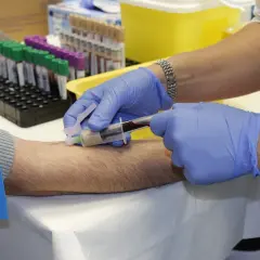 Pobieranie krwi do badań. Rękawiczki, opaska uciskowa i probówki z krwią czekają na dalsze analizy. **APTT** jest jednym z badań, które można wykonać.