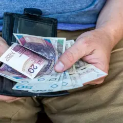 Dłonie trzymają portfel z polskimi banknotami. Czy to dodatek pielęgnacyjny, czy zasiłek pielęgnacyjny?