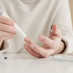 Mężczyzna mierzy poziom cukru we krwi, co może być ważne w kontekście kwasicy mleczanowej.