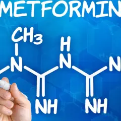 Struktura metforminy i jej potencjalne metformina skutki uboczne. Ręka pisze wzór chemiczny na niebieskim tle.