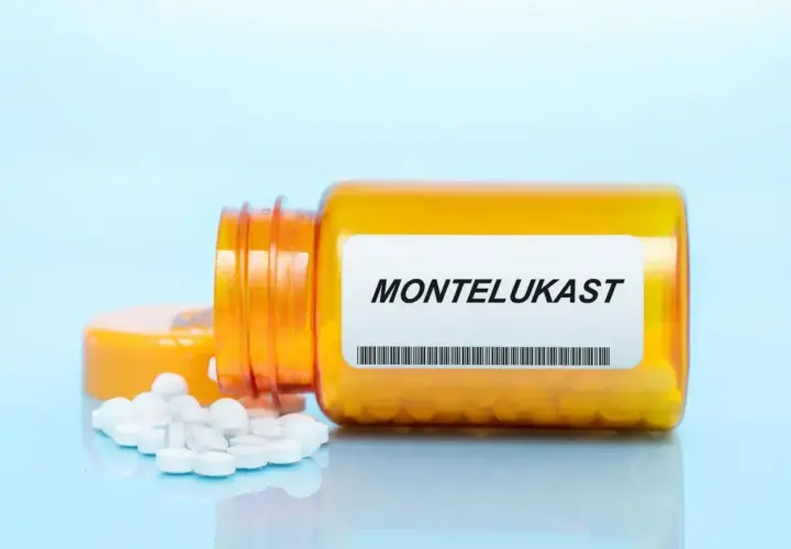 Pomarańczowa buteleczka leku z etykietą "MONTELUKAST" i rozsypanymi tabletkami.