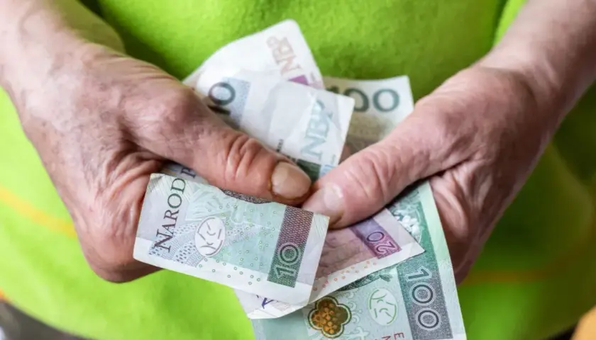 Dłonie trzymają polskie banknoty. Czy to już kwota na rentę socjalną 2026?