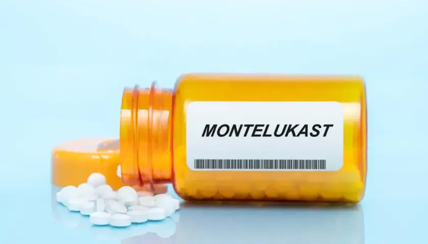 Pomarańczowa buteleczka leku z etykietą "MONTELUKAST" i rozsypanymi tabletkami.