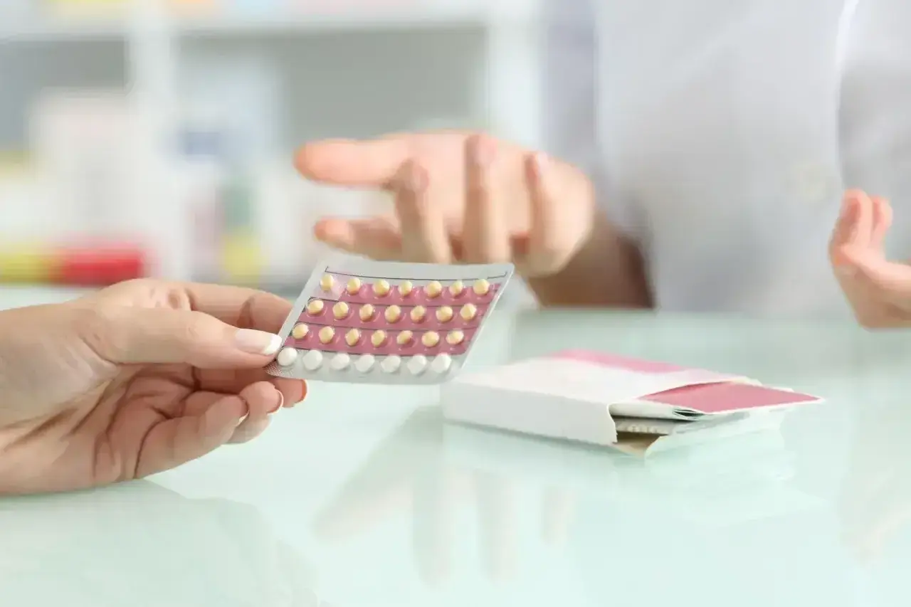 Dłoń trzyma blister tabletek antykoncepcyjnych. Farmaceuta wyjaśnia, bibloc na co.