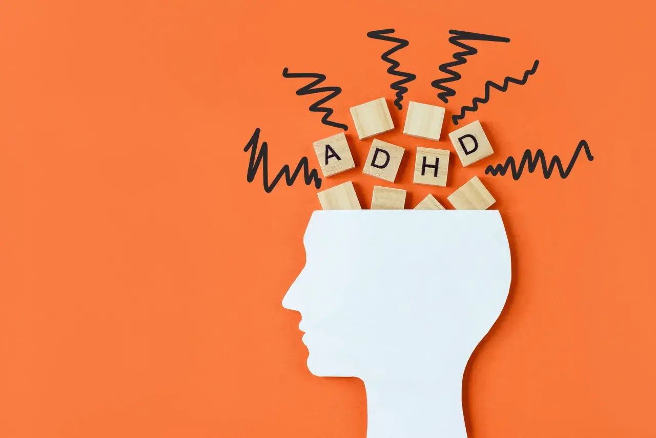 Biały profil głowy z literami "ADHD" i chaotycznymi liniami symbolizującymi myśli, odzwierciedlającymi wyzwania związane z ADHD u dorosłych.
