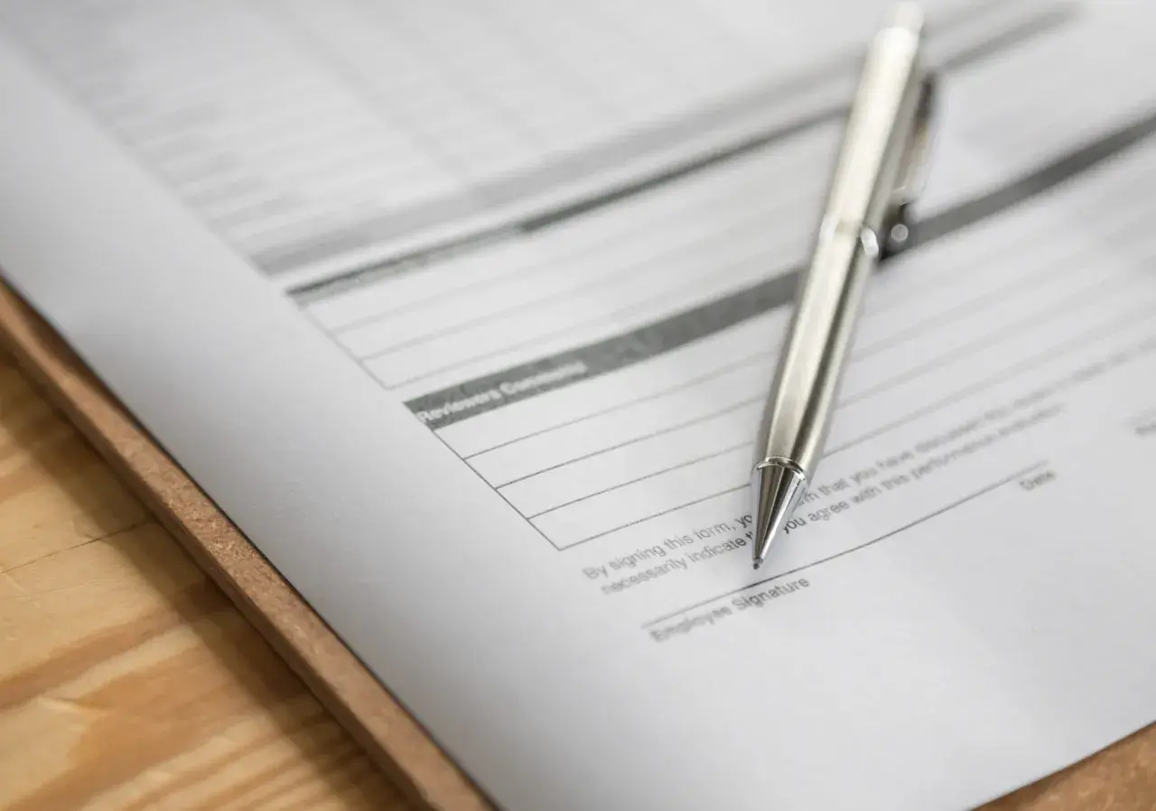 Srebrny długopis leży na dokumencie z polem "Employee Signature". To zap-3, gotowy do podpisu.