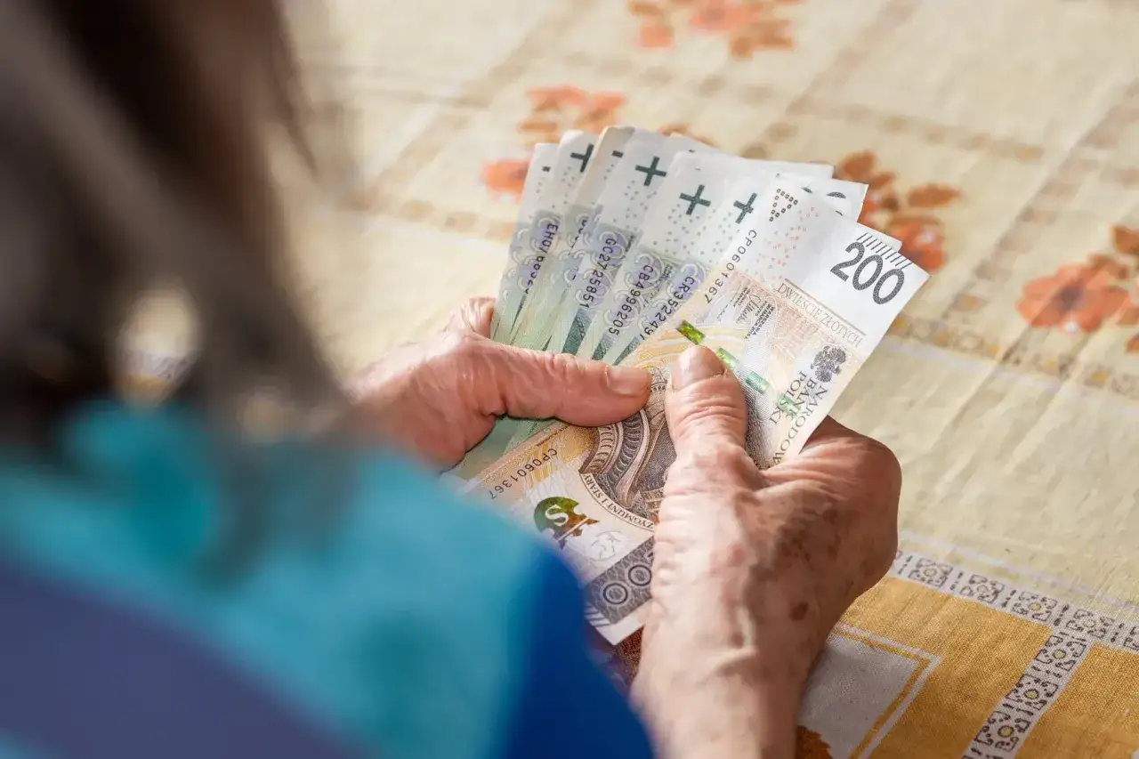 Dłonie liczą banknoty 200 zł. Może to wsparcie z ZUS, np. 500 plus dla chorych na raka, ułatwiające życie w trudnych chwilach.