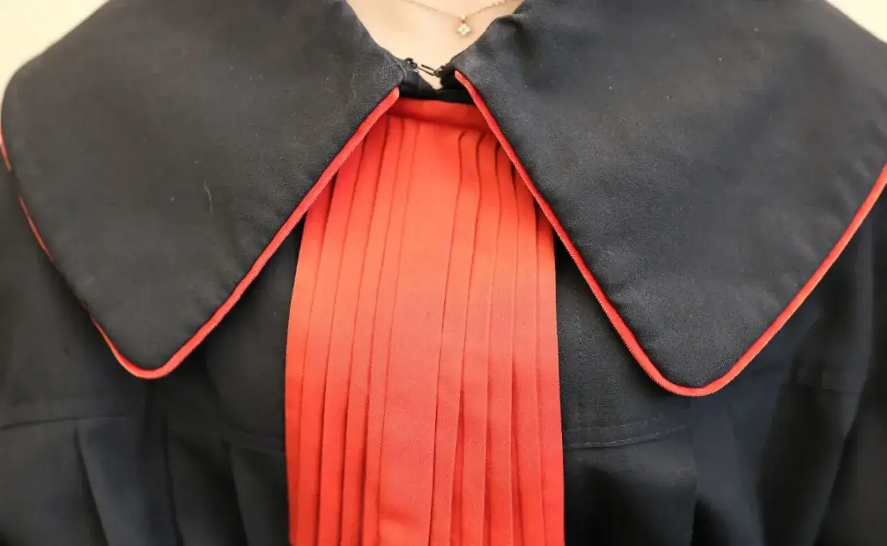 Czarne szaty z czerwonym żabotem, symbolizujące powagę i profesjonalizm. Kontrasygnata w sądzie.