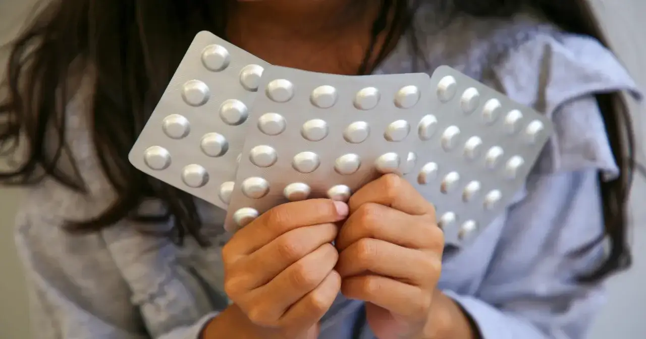 Dłonie dziecka trzymają opakowania tabletek, być może ritalin.