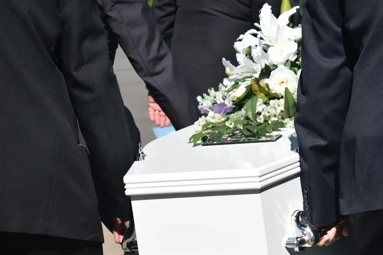 Uroczysty pogrzeb. W białej trumnie z kwiatami niesionej przez żałobników, zastanawiamy się, ile kosztuje pogrzeb.