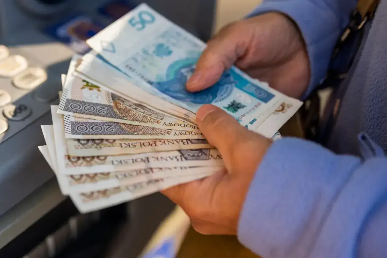 Ręce trzymające stos banknotów 200 zł i 50 zł. Zastanawiasz się, ile można dorobić do emerytury?