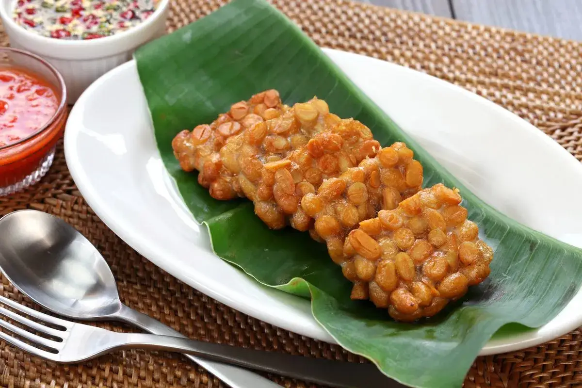 Smażony tempeh, czyli co to jest? Chrupiące kotleciki z soi na liściu bananowca, podane z sosami.
