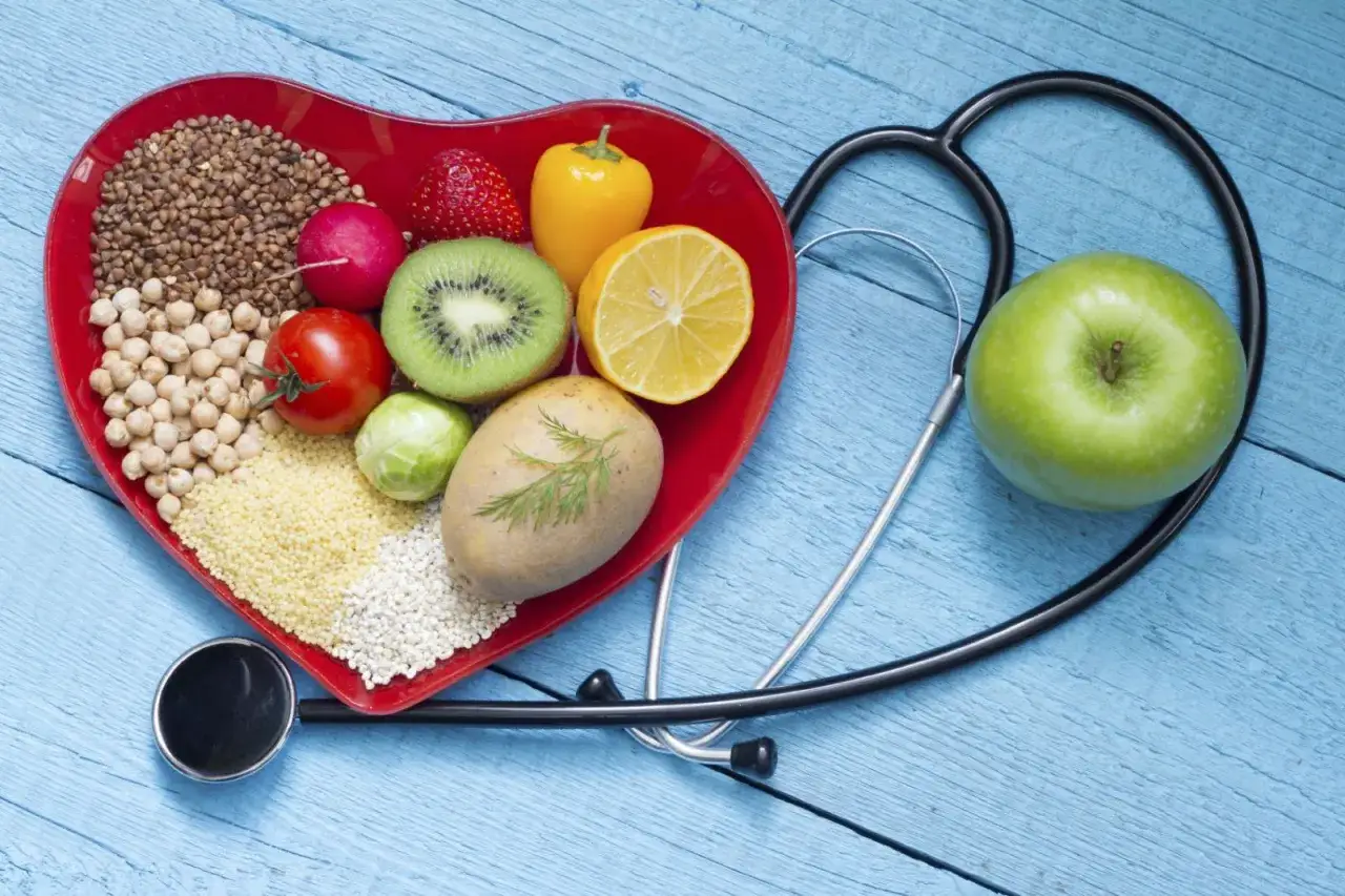Serce z jedzeniem i stetoskopem symbolizują zdrową dietę, która może pomóc w obniżeniu cholesterolu.