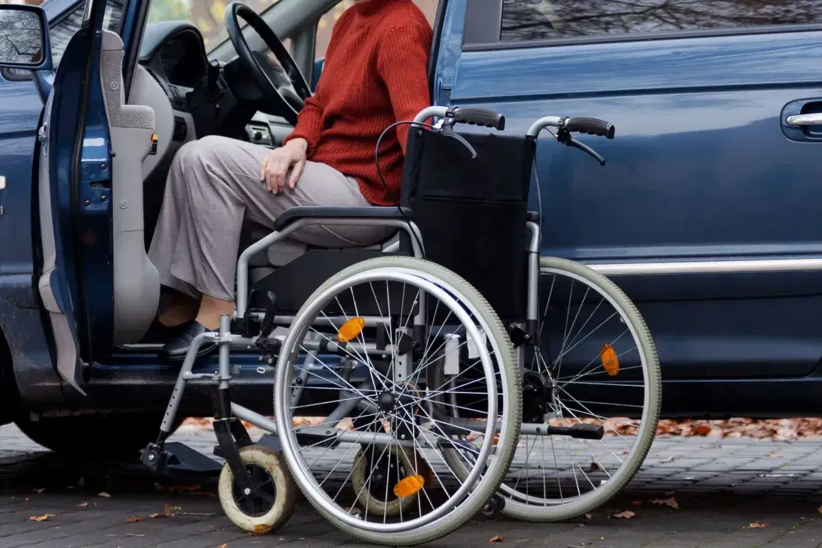 Osoba na wózku inwalidzkim wsiada do samochodu, co ułatwia ulga rehabilitacyjna na samochód.